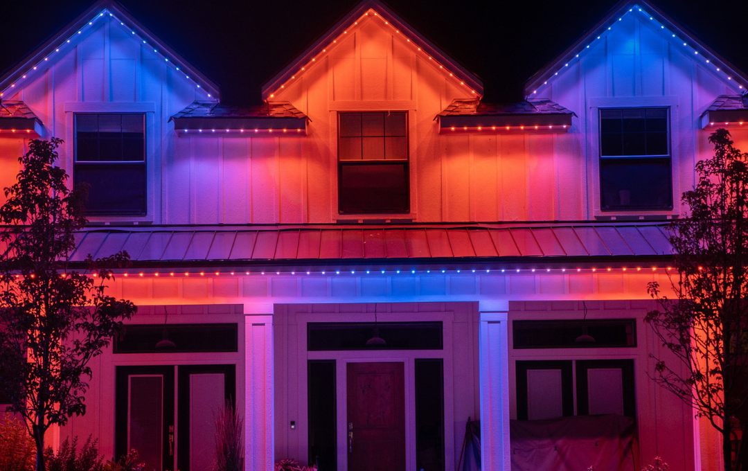 The same home lit in a full rainbow of colors across the roofline