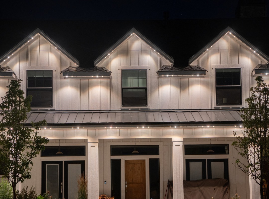 A two-story home at night with warm white permanent LED lighting outlining every roofline and the front porch